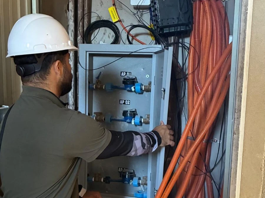 Técnico verifica quadro de medidores hidráulicos em área comum